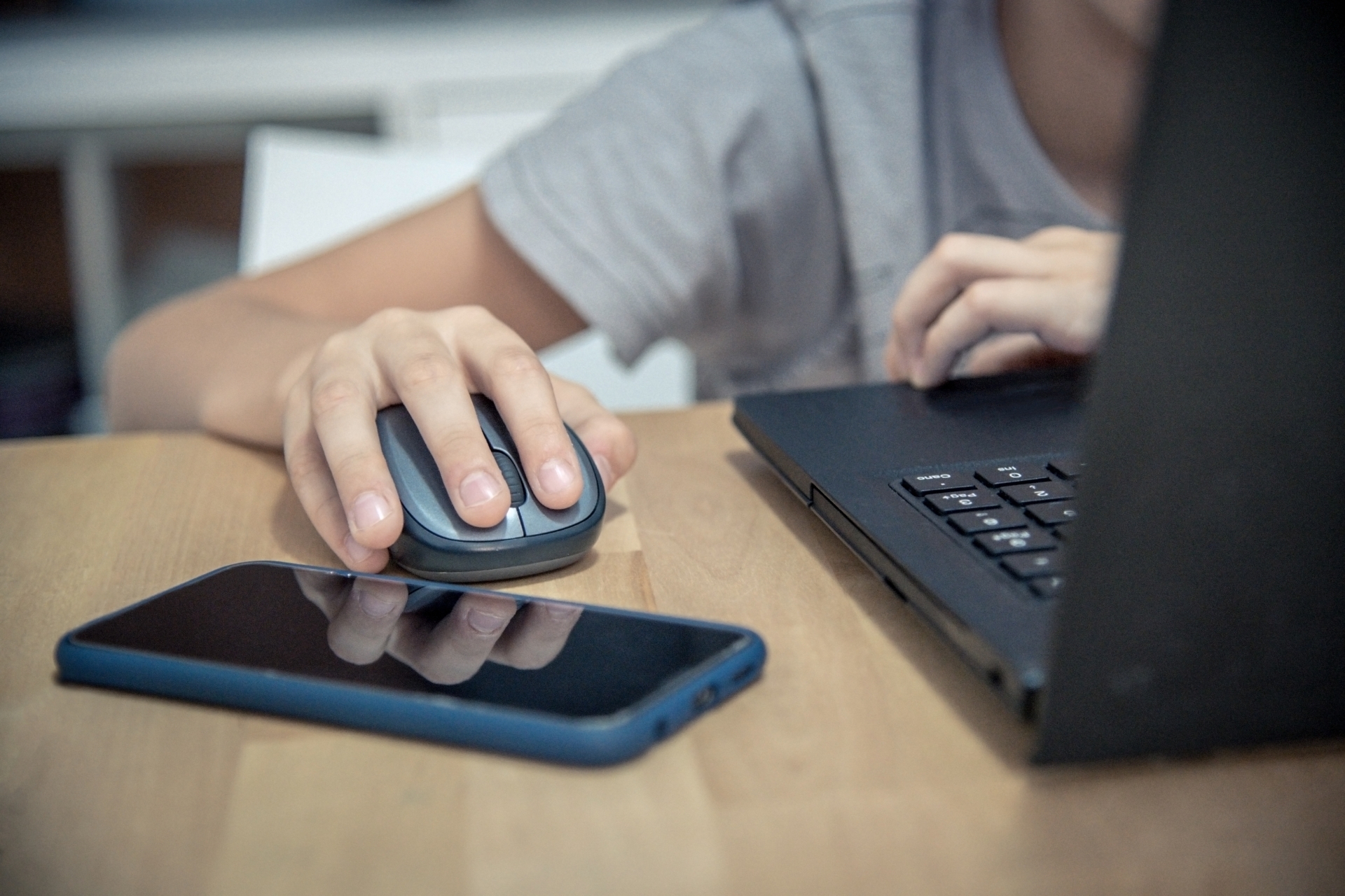 Nahaufnahme von Laptop, Maus, Smartphone und Hand.